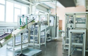 A modern industrial facility showing various machinery and equipment for system integration and engineering processes. The space is well-lit, featuring a conveyor belt and multiple units designed for efficient engineering operations.