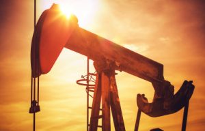 An oil pump jack operates against a sunset backdrop, symbolizing the oil recovery industry. This image reflects the sector's importance in Calgary's engineering and consulting landscape.