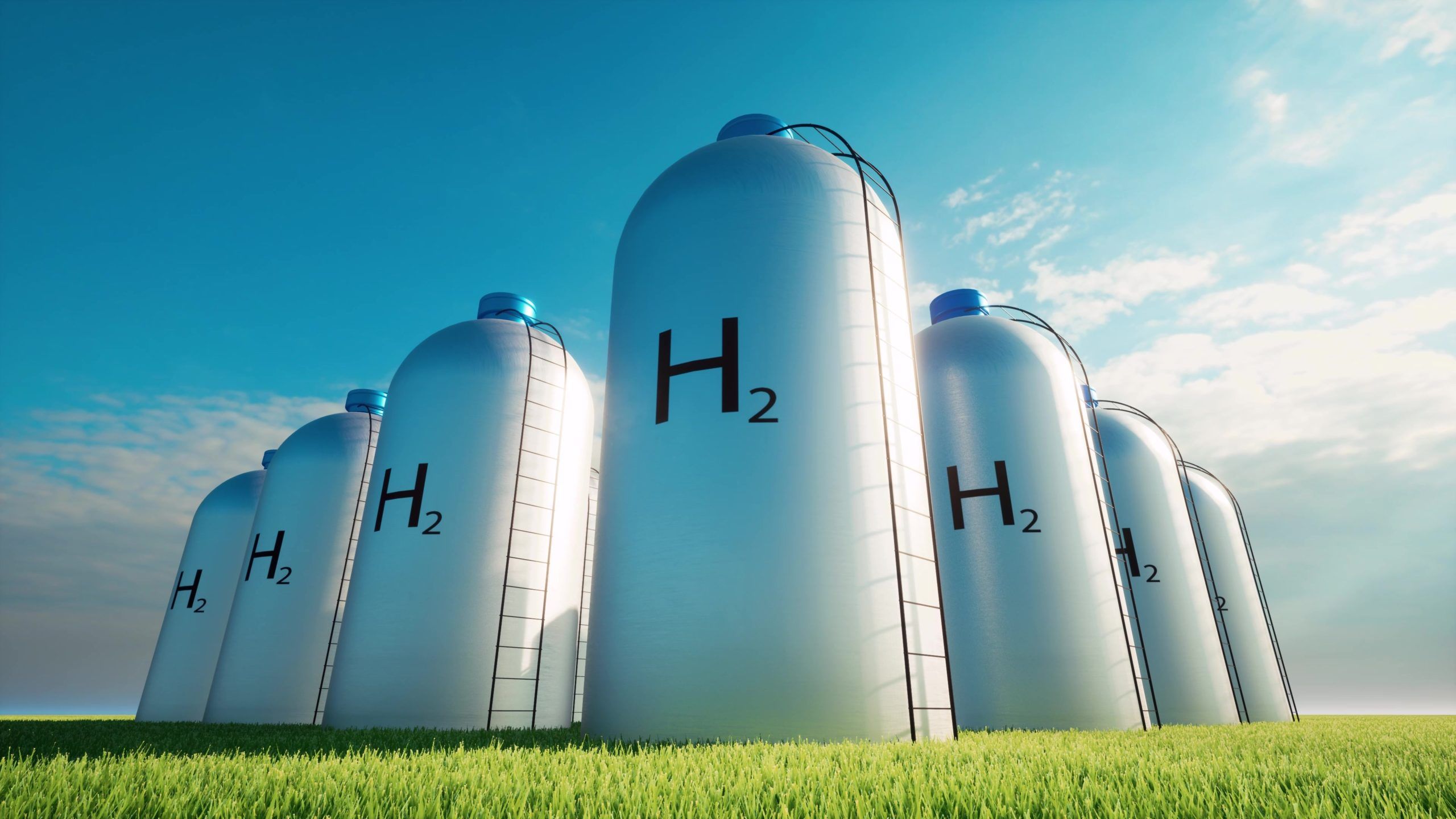 Six large hydrogen storage tanks are positioned in a green field under a clear blue sky. Each tank prominently displays the chemical symbol for hydrogen (H2), showcasing the focus on hydrogen energy solutions.