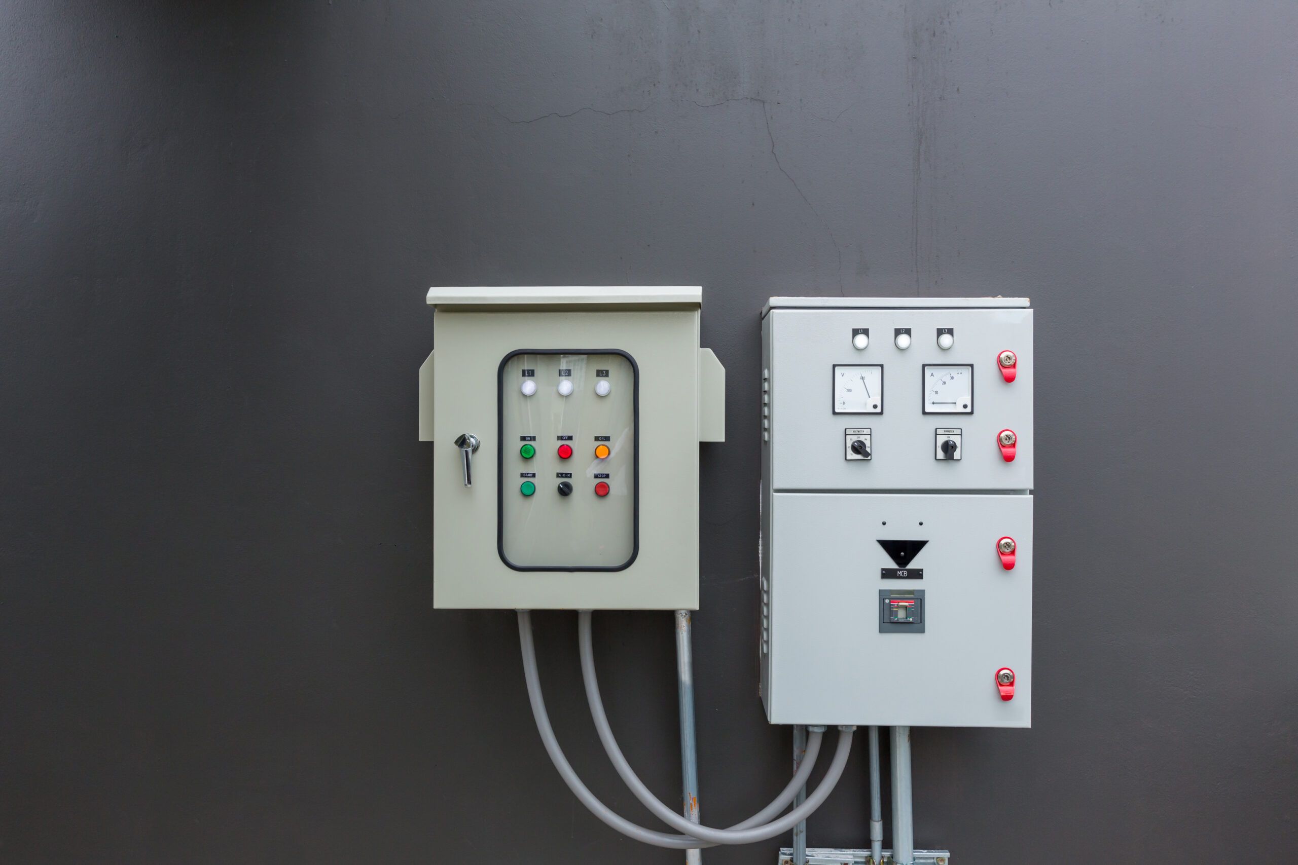 Outdoor electrical enclosures with control panels and circuit gauges mounted on a grey wall