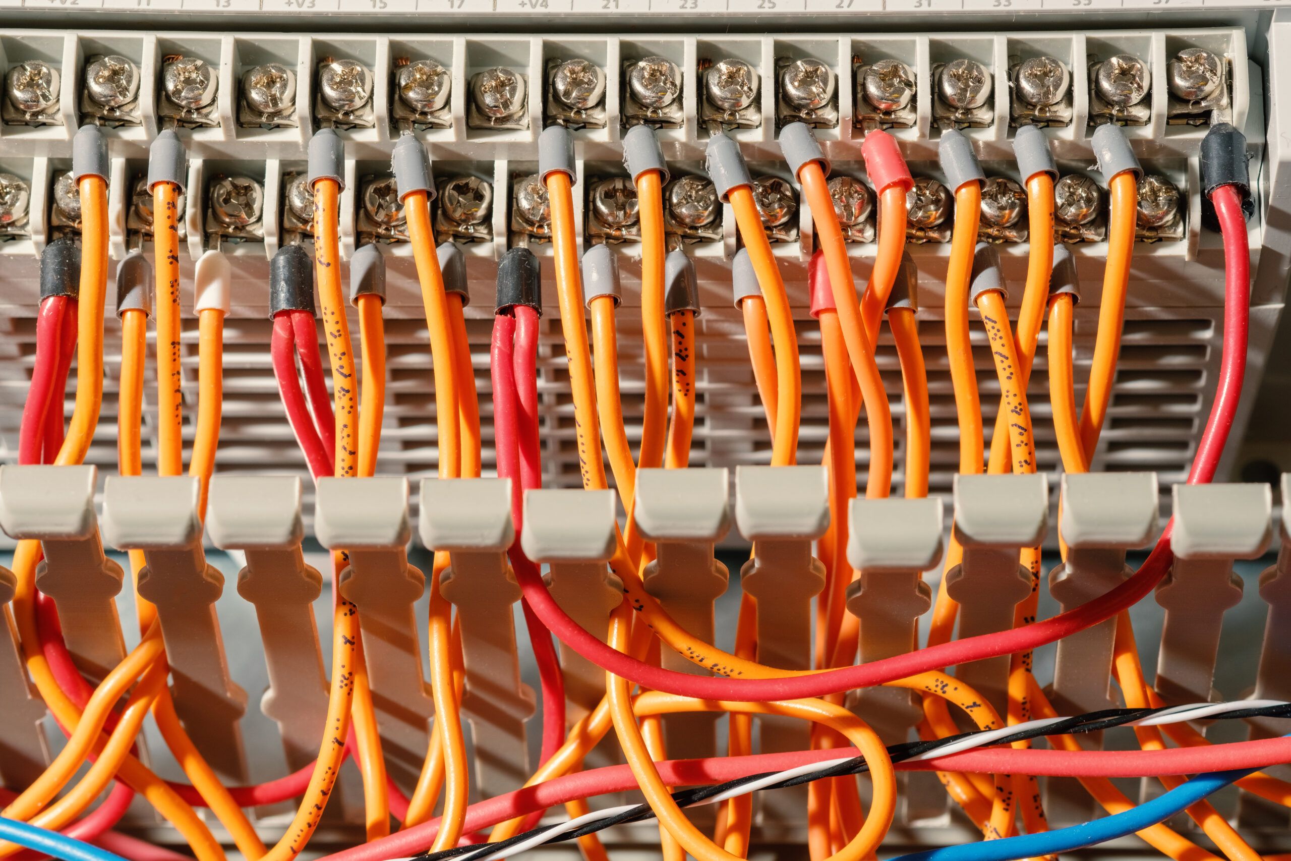 Close‑up of orange and red wires in a terminal block, some insulation scorched—evidence of overload and heat build‑up.