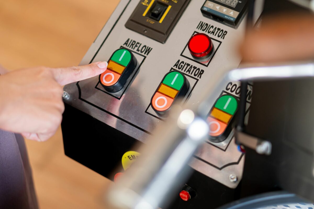 Hand pressing airflow button on advanced industrial control panel with labeled functions.