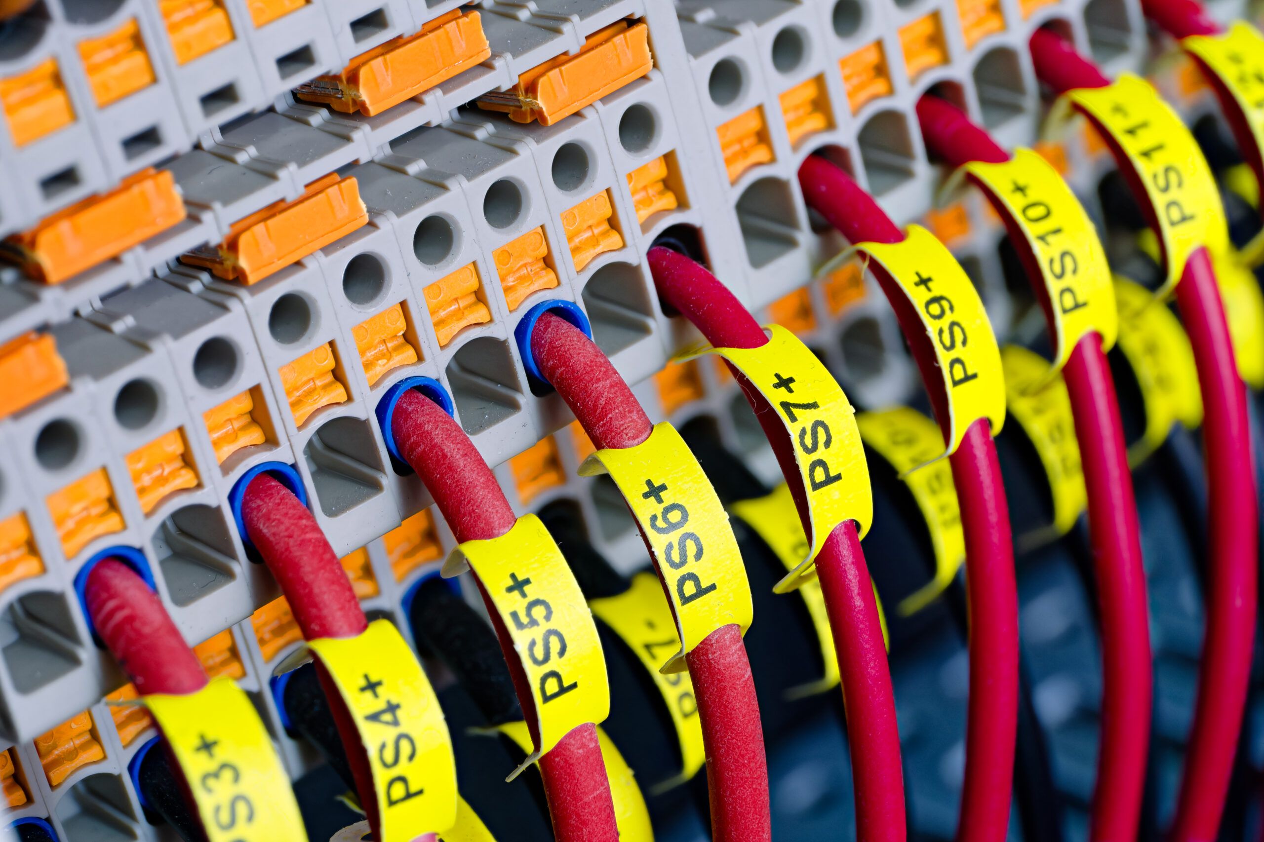 Close-up of labeled red wires connected to terminal blocks in an electrical panel.