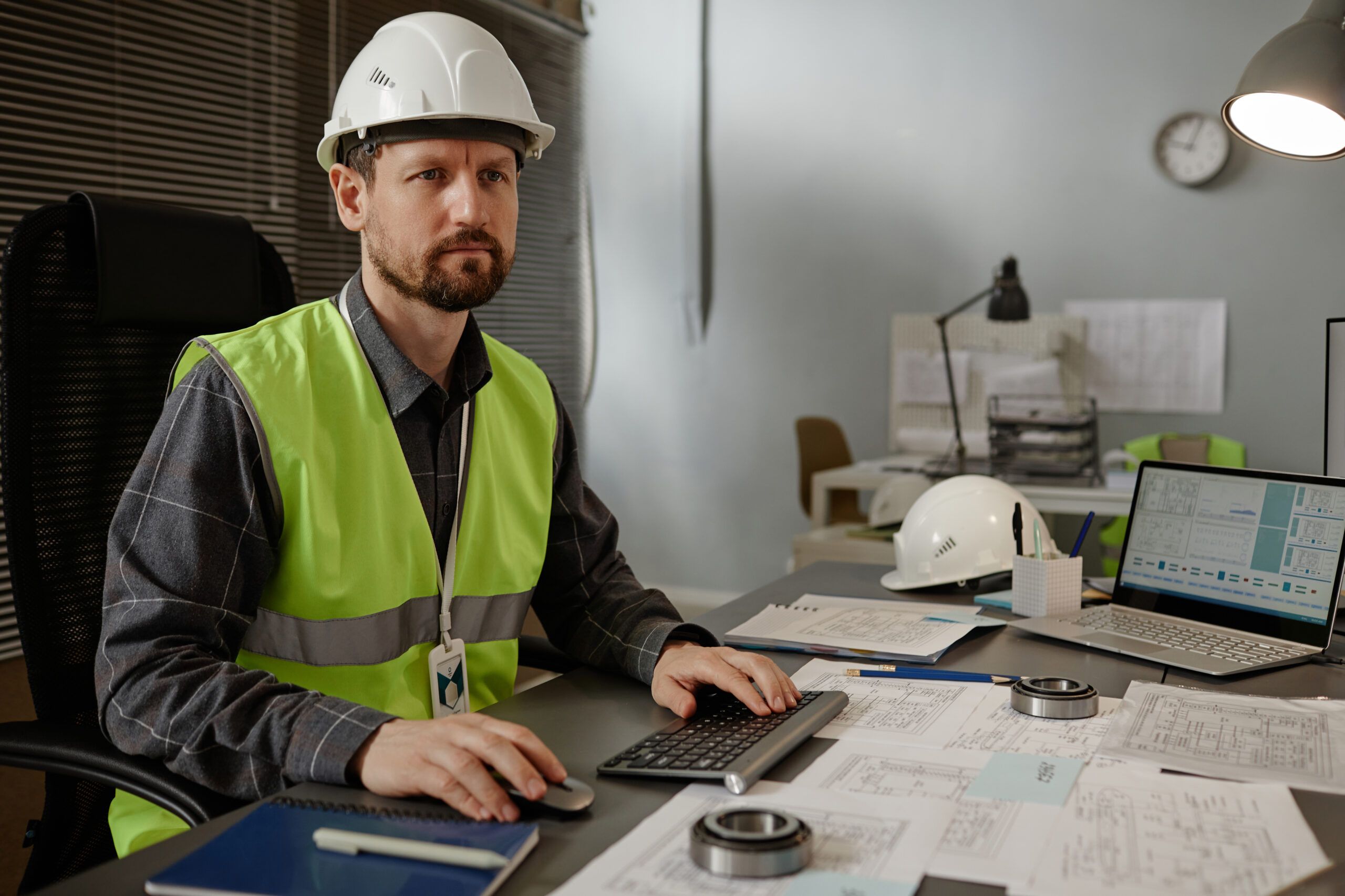 Instrumentation engineer at desk reviewing technical schematics and control system diagrams on computer.