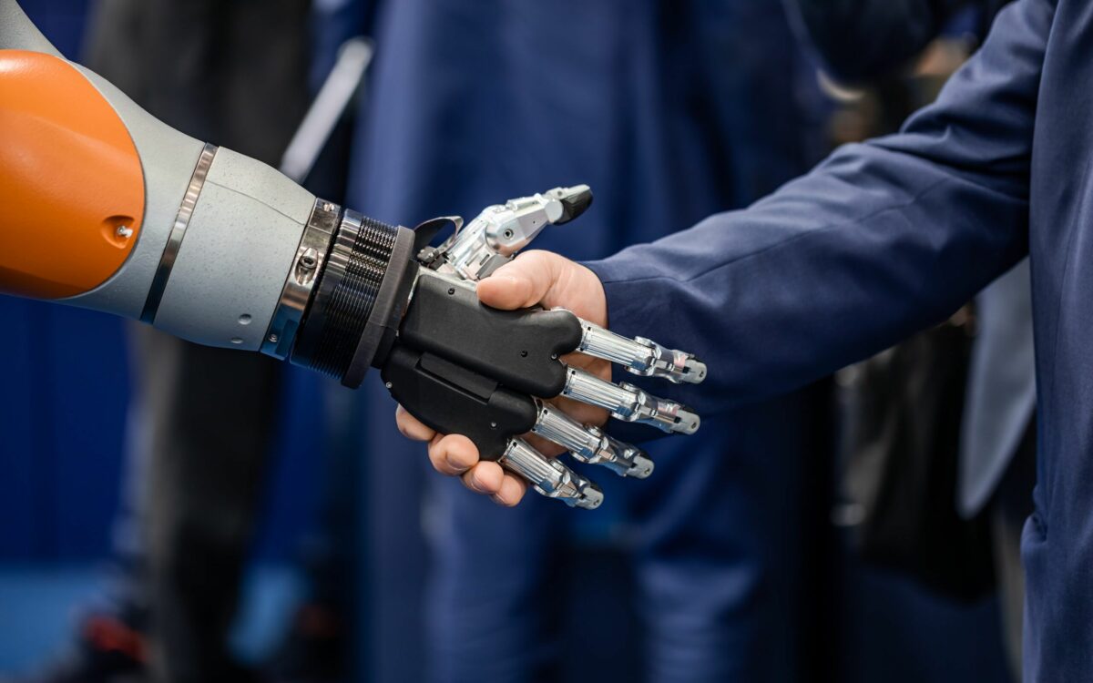 Robot and human hand shaking to symbolize robotics integration in modern industry