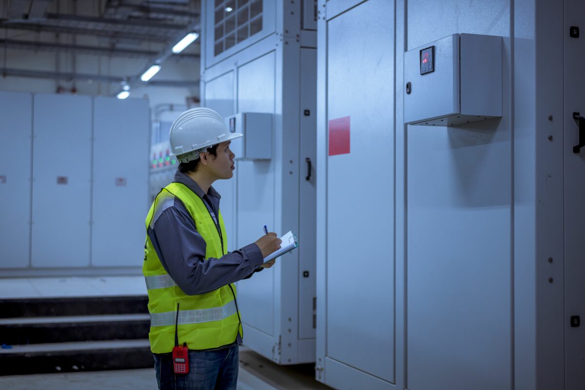 Electrical technician conducting preventive inspection on power distribution cabinets in industrial facility