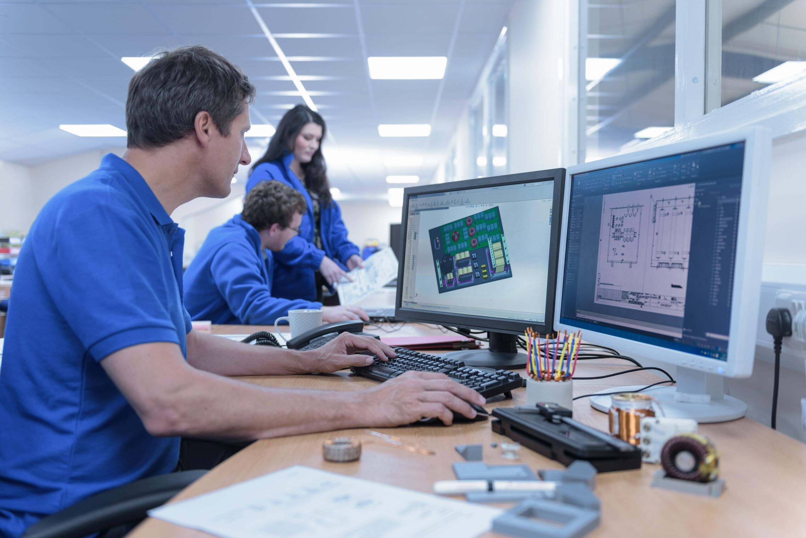 Engineers working with circuit design and simulation software in a collaborative office environment.