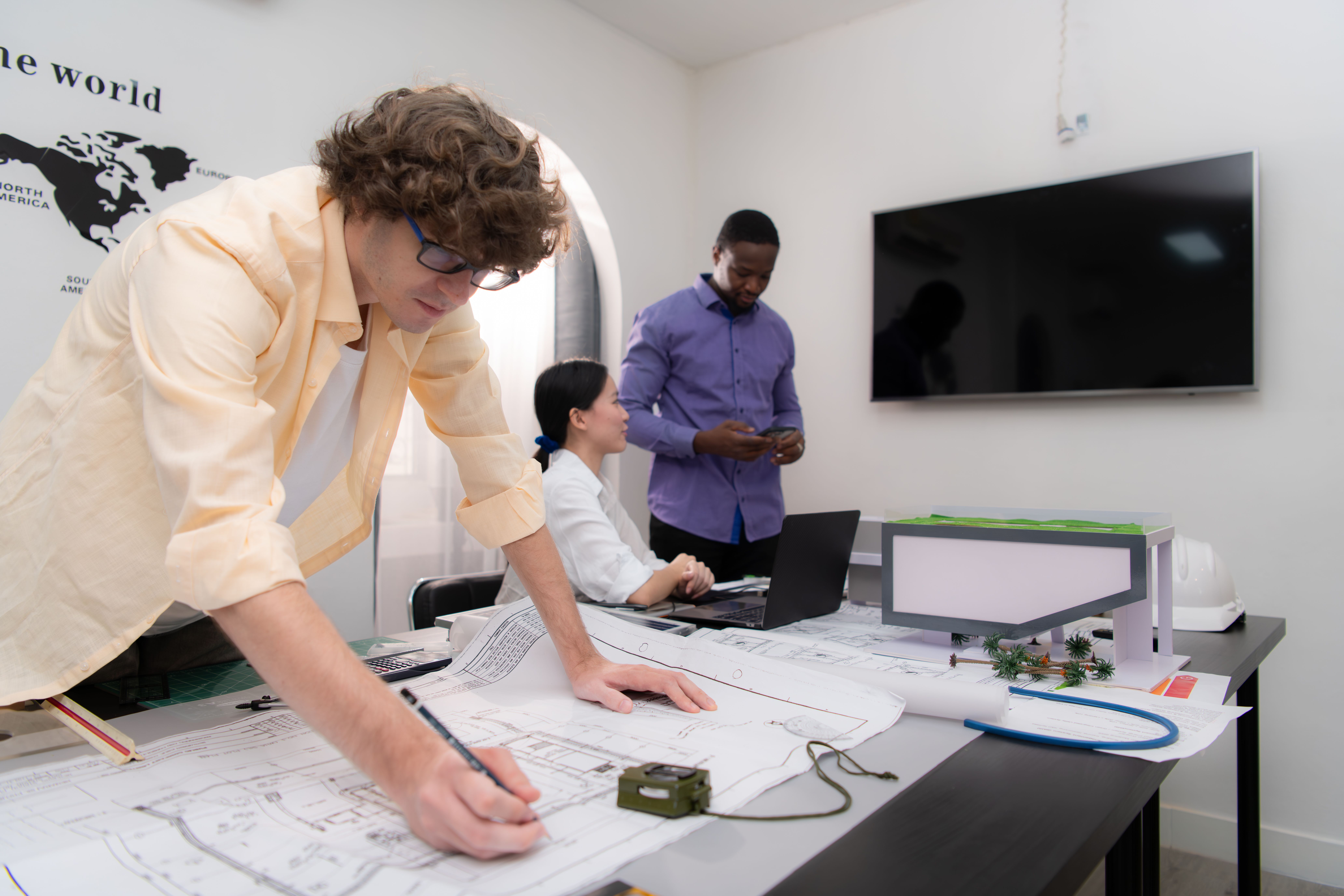 Electrical designers working together on technical drawings and engineering plans in a modern office.