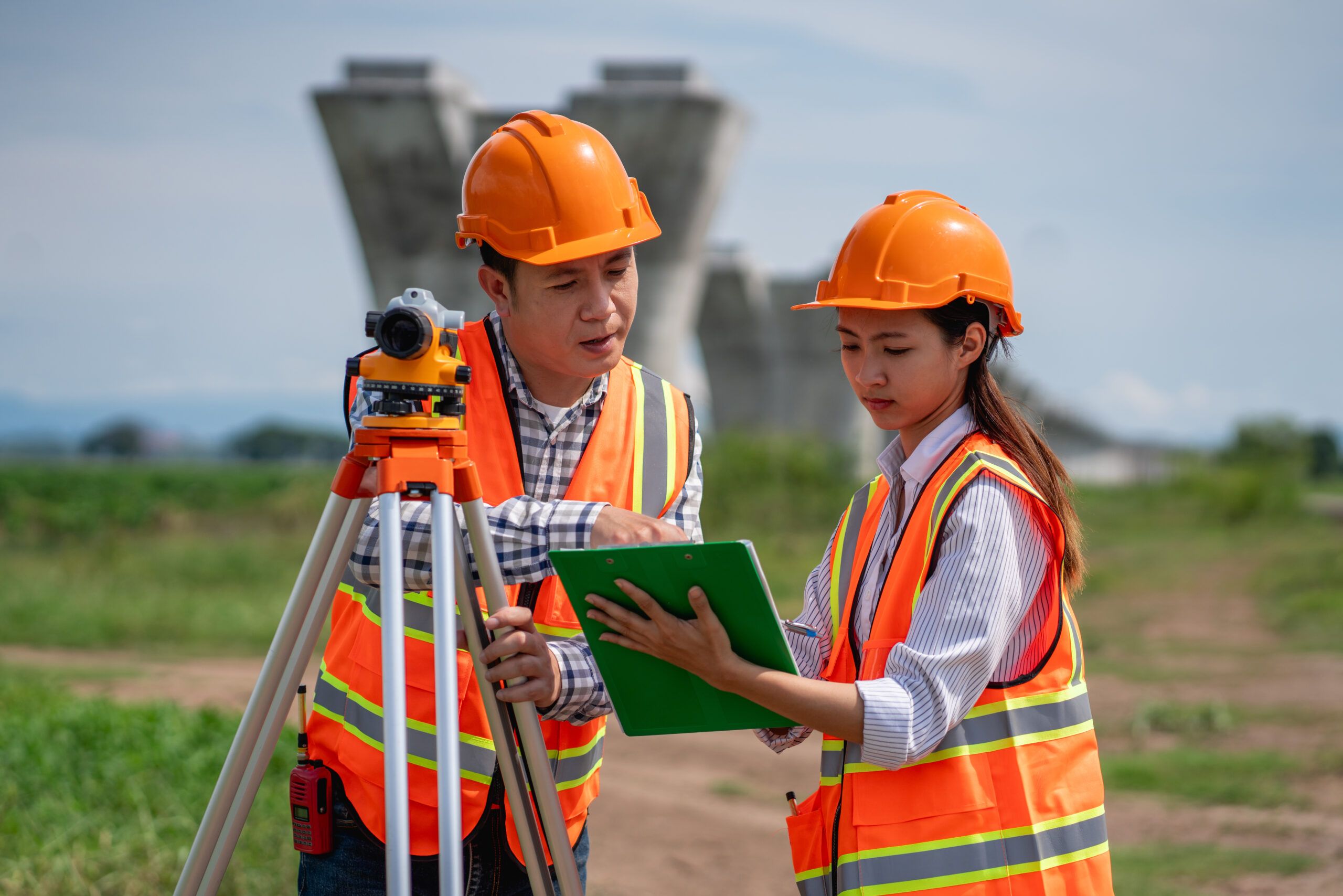 Civil and structural engineers conducting field surveying with tripod equipment at a construction site.