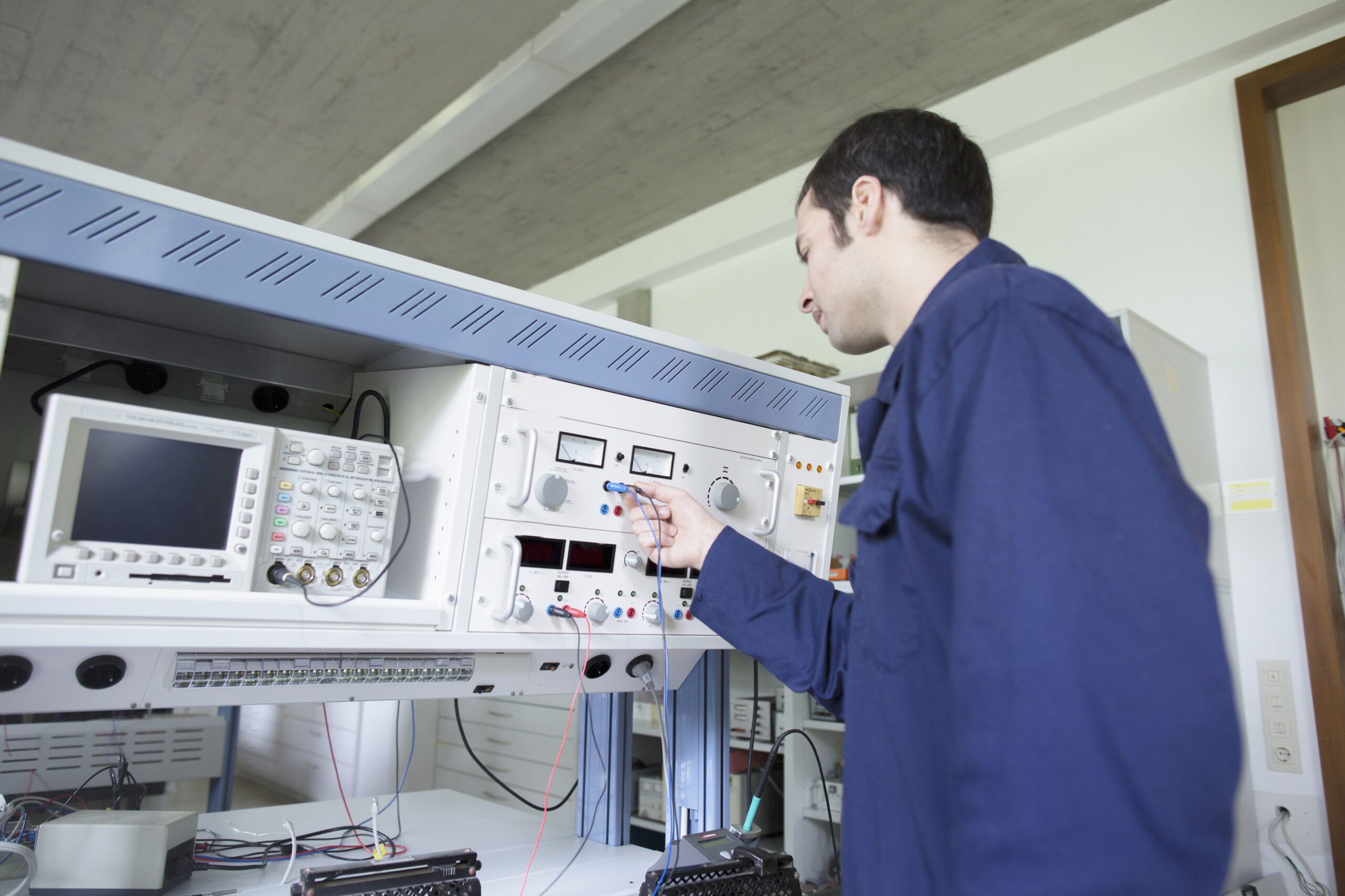 Technician performs high-precision calibration on an electronic instrument using specialized test equipment within a workshop setting, verifying accuracy before field installation.