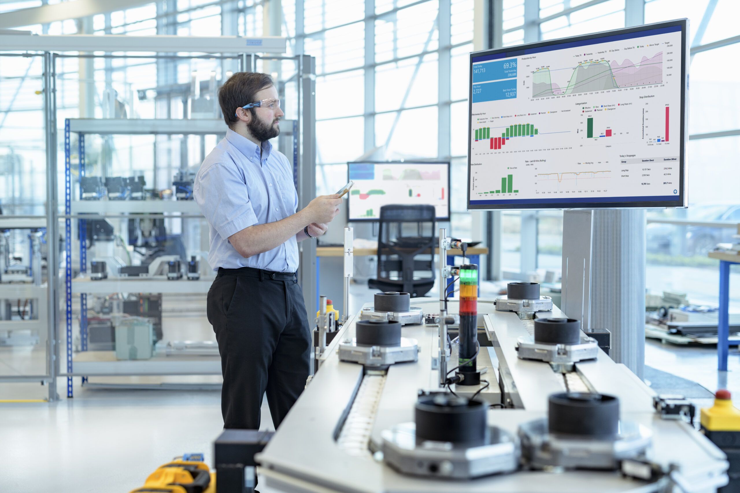 Civil engineer reviewing industrial design software dashboards and production data on a monitor inside a modern engineering lab